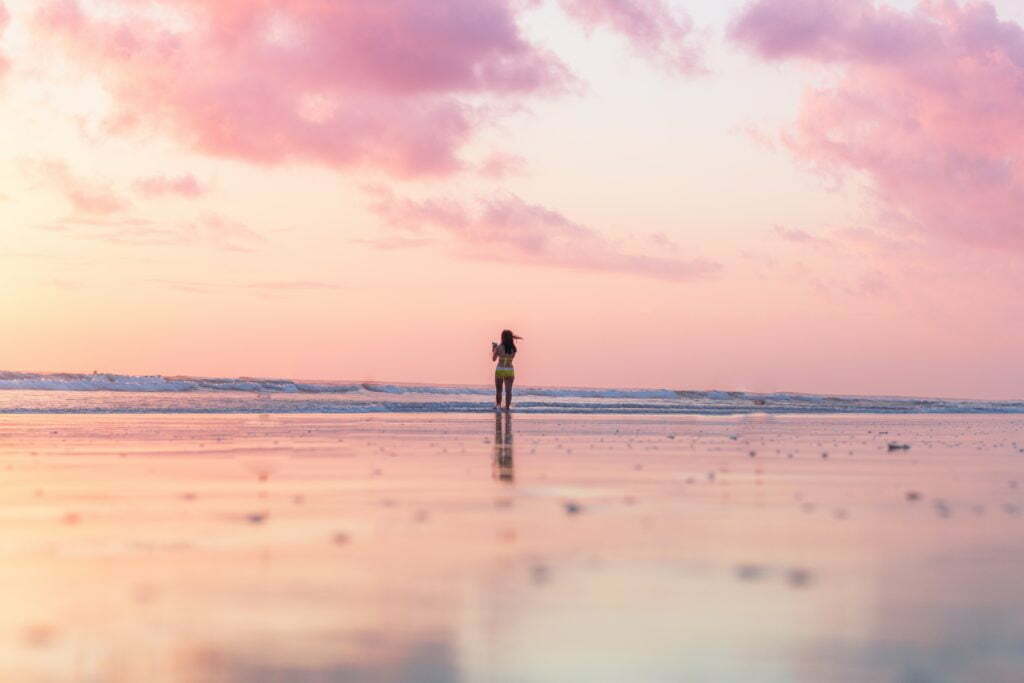 woman standing on seashore in front of body of water