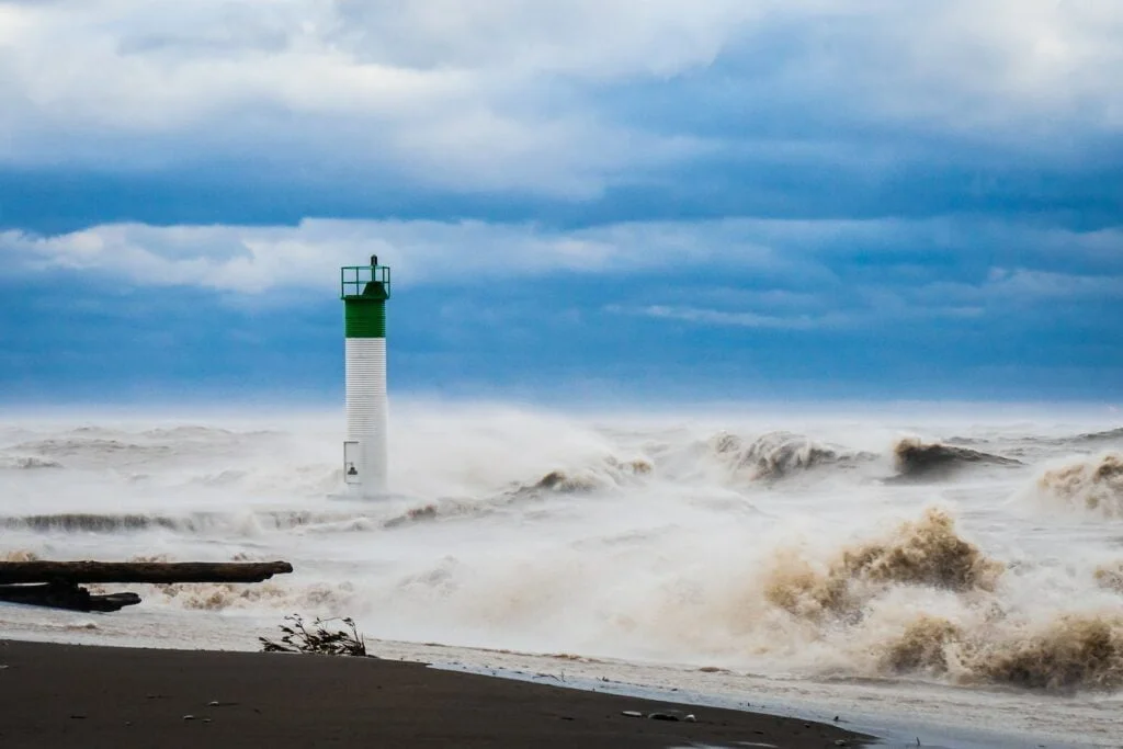 white and green lighthouse on beach shore under blue sky during daytime
