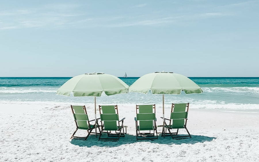 green chairs under umbrellas on shore