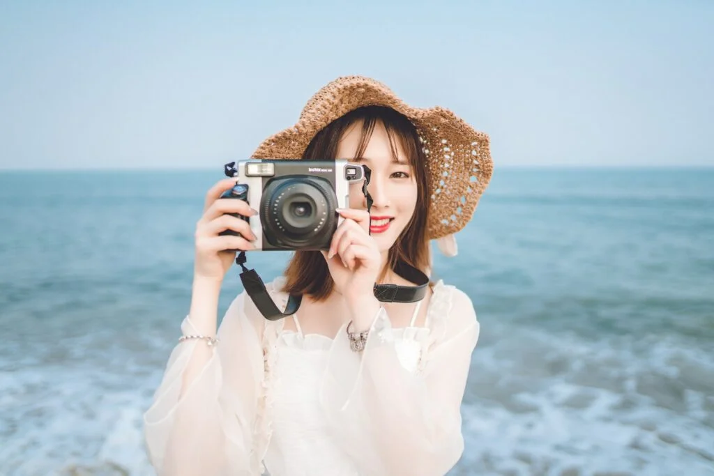 woman holding camera at the beach