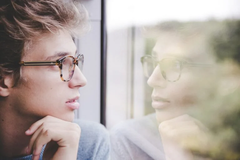 A looking at their reflection with a puzzled expression.