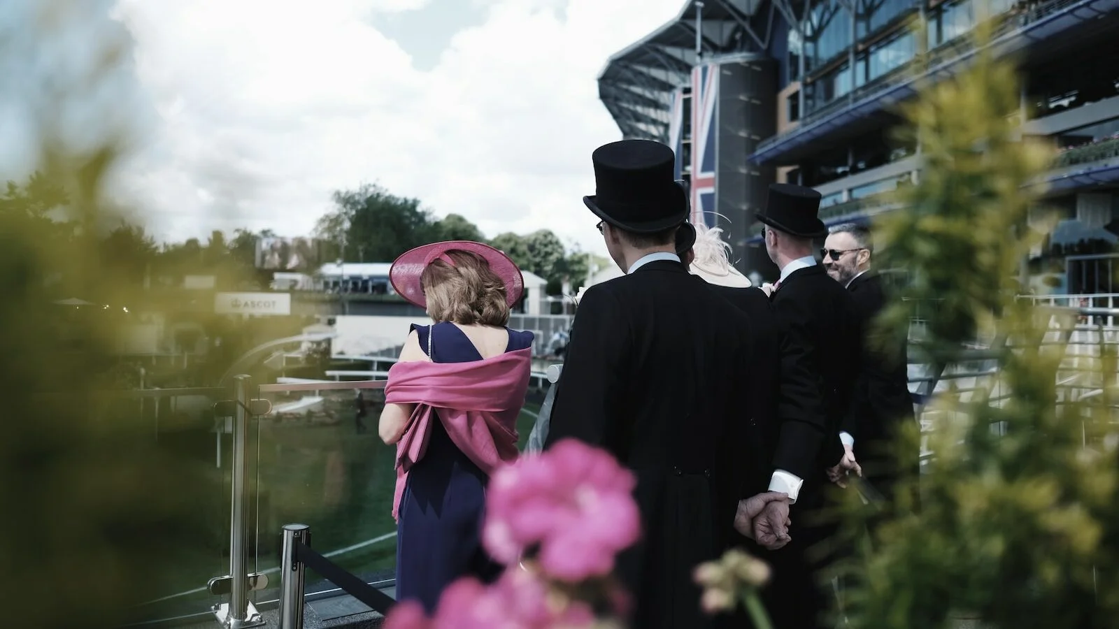 men in suit standing behind woman wearing pink hat and scarf