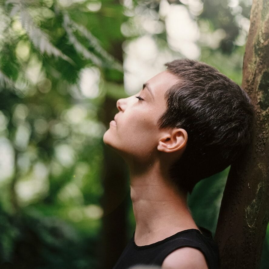 boy leaning back on tree