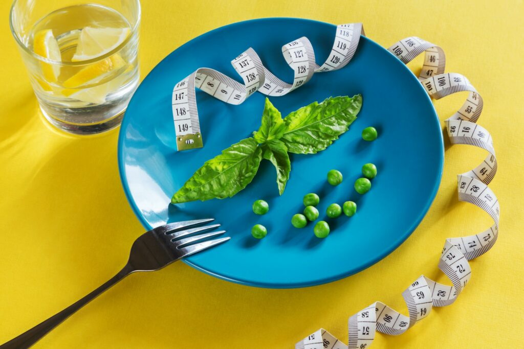 a blue plate topped with green vegetables and measuring tape