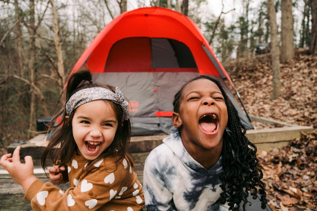 a couple of young girls standing next to a tent