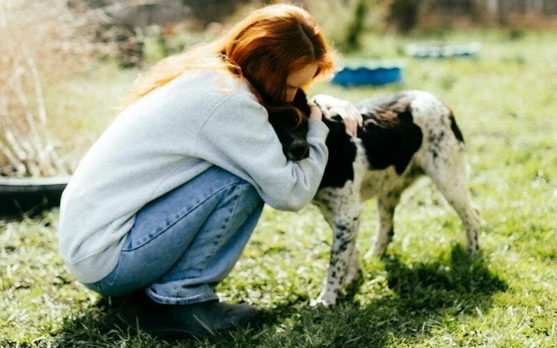 a woman kneeling down next to a dog