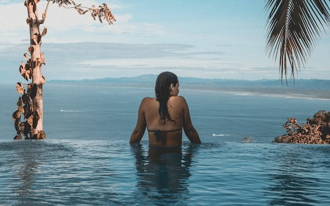 woman wearing black bikini tap swimming on body of water between trees