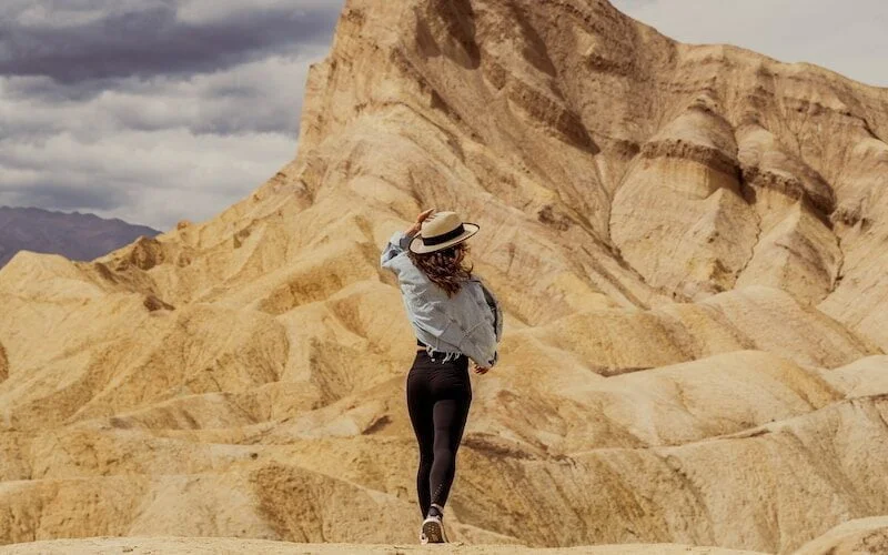 a woman in a hat is walking in the desert