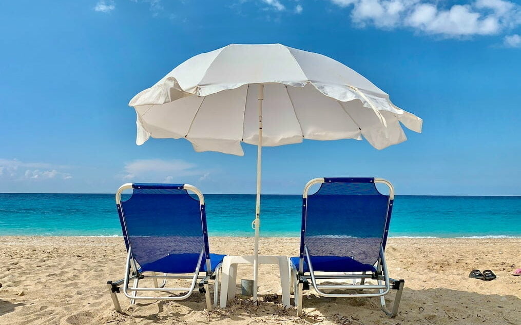 blue and white chair under white umbrella on beach during daytime