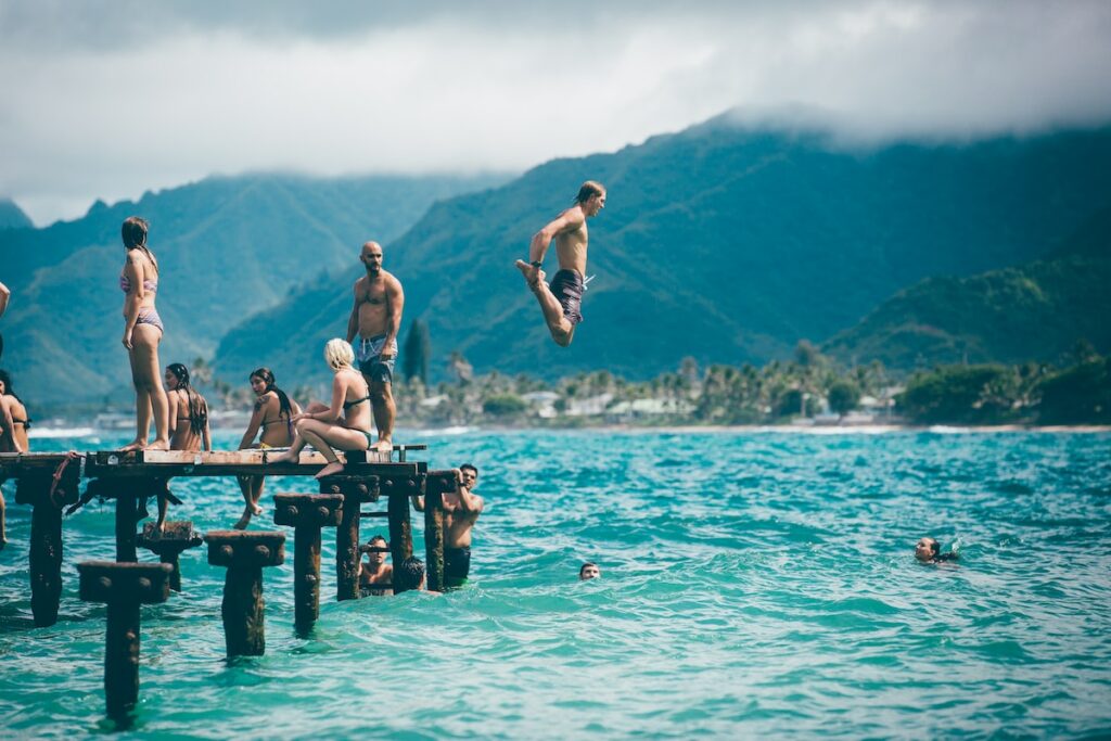 man diving from dock with people