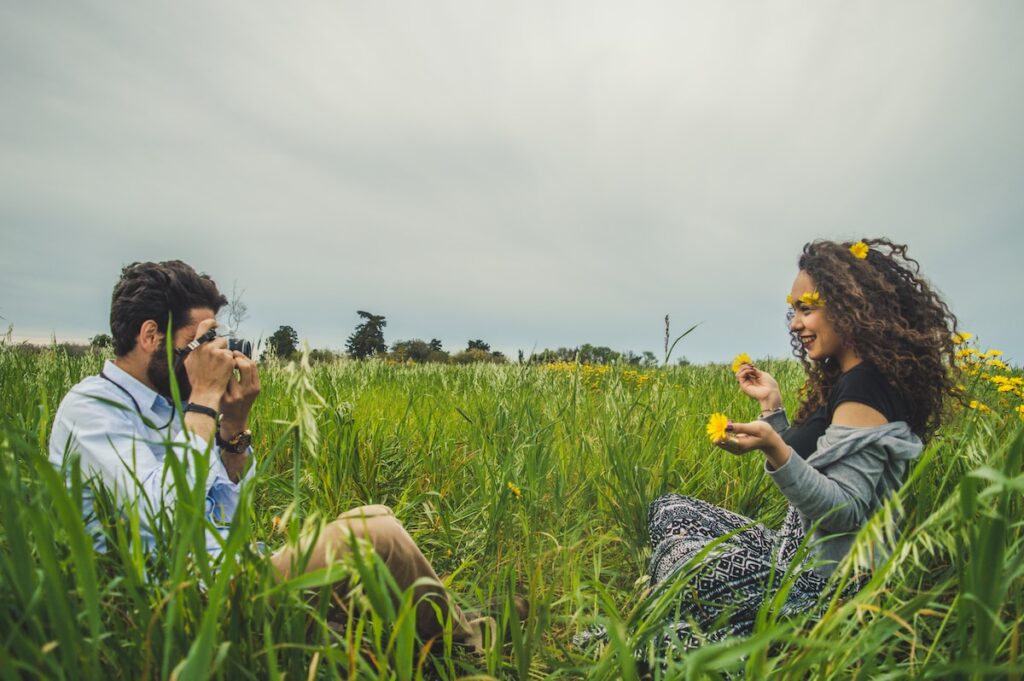 man taking photo of woman sitting on green grass