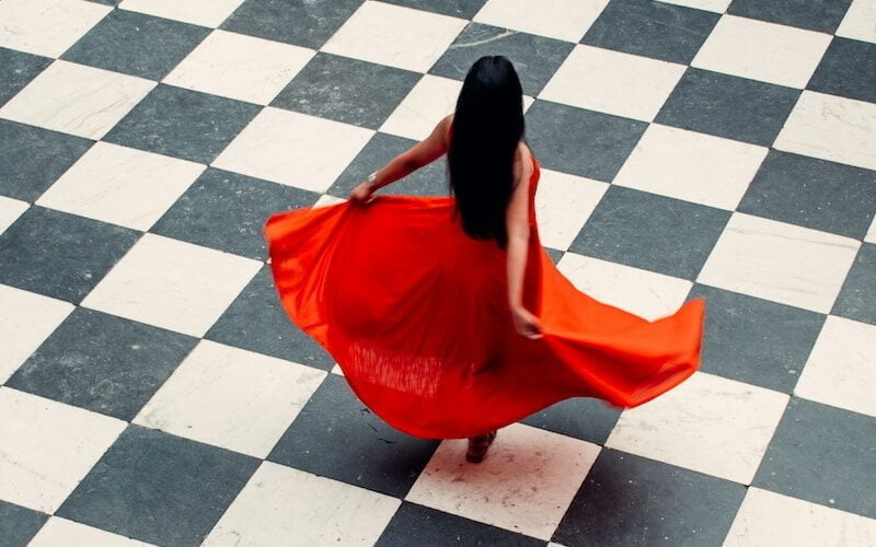 woman in red dress walking on gray and white floor tiles