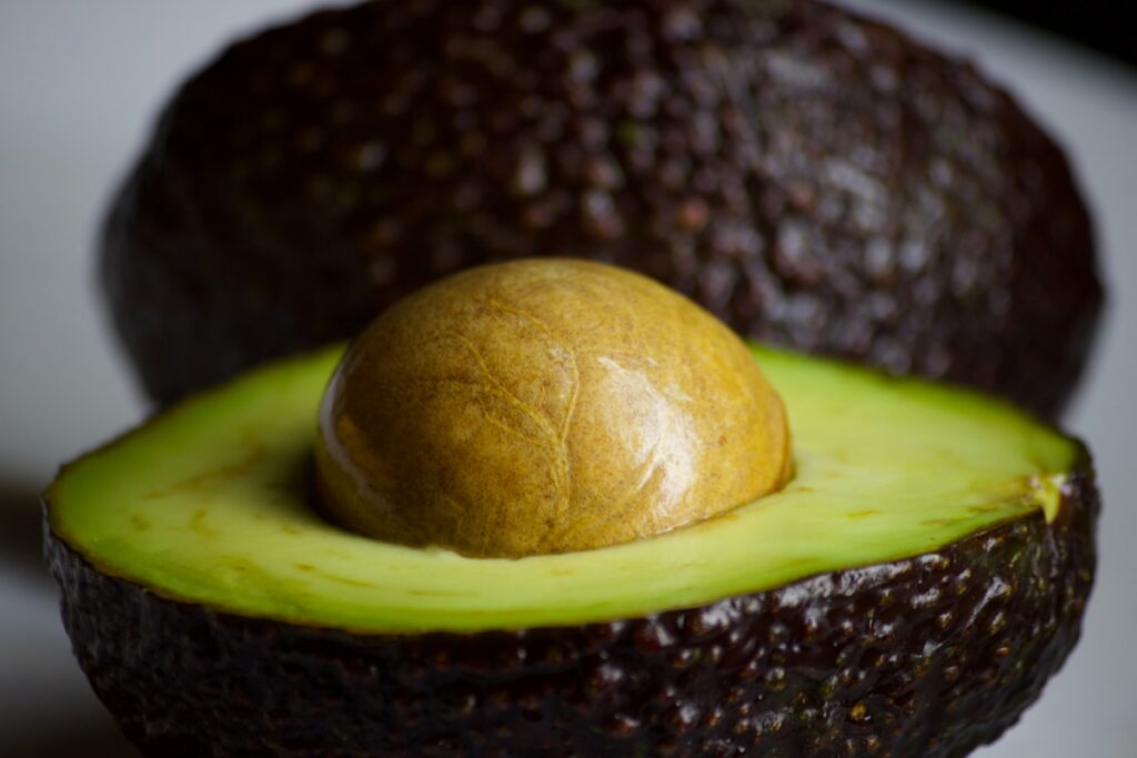 An avocado cut in half with a whole avocado in the middle