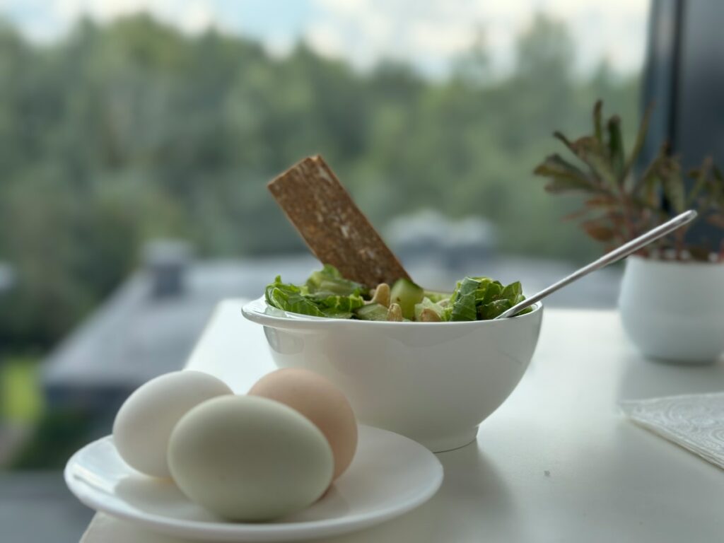 A bowl of salad and two eggs on a table