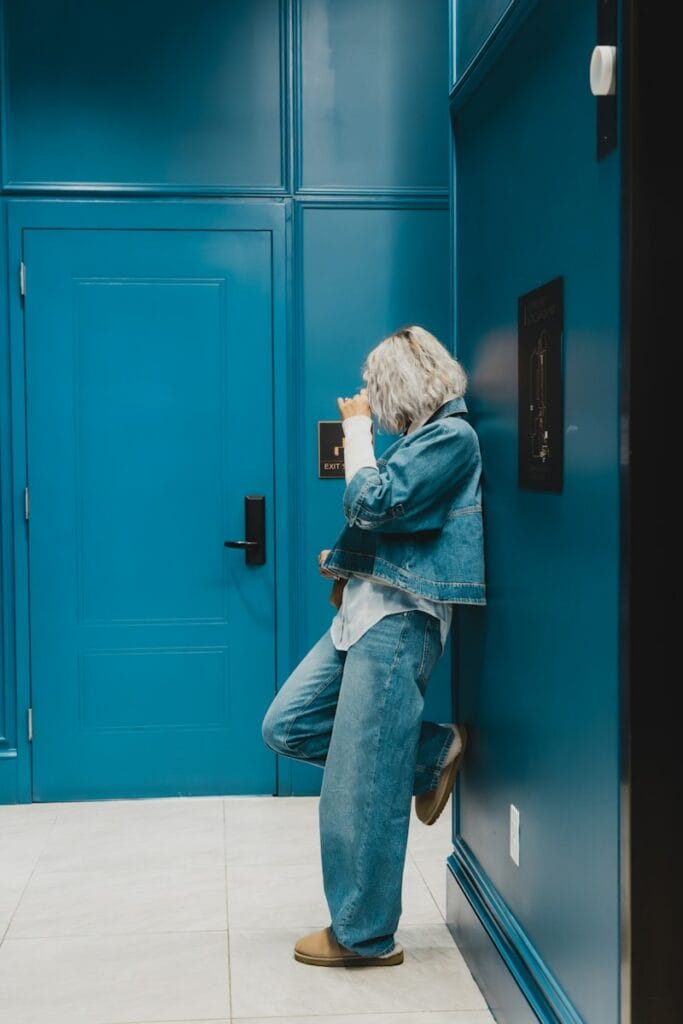 A person leans against a bright blue wall.