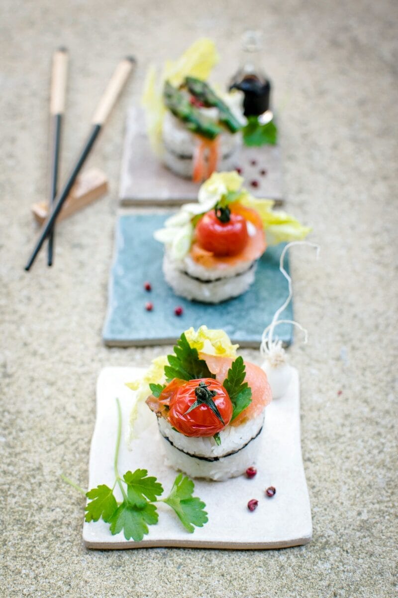 sushi with toppings on white board near chopsticks