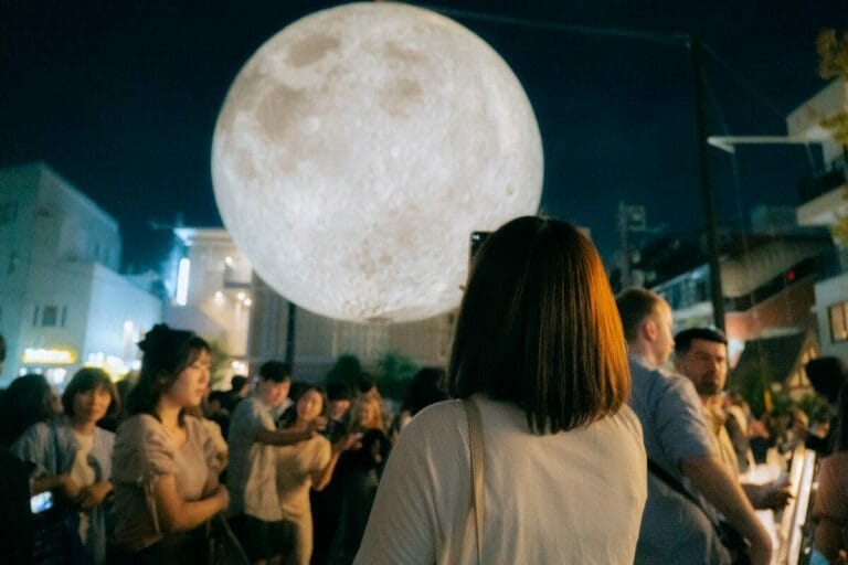 a group of people standing around a giant moon